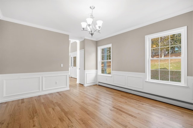 unfurnished dining area featuring a chandelier, a wealth of natural light, baseboard heating, and ornamental molding