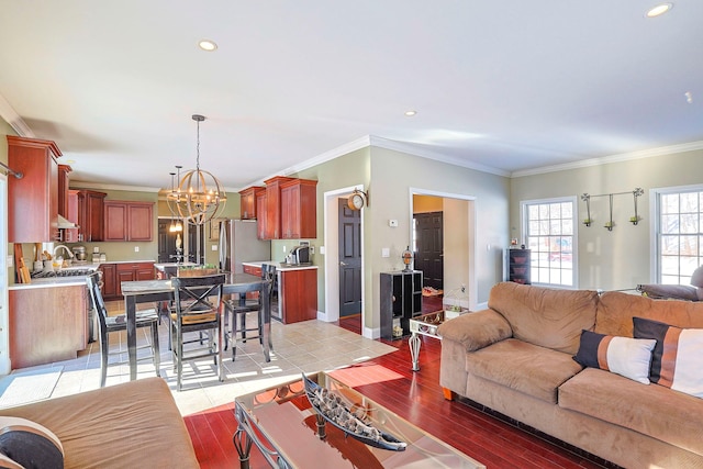 living room featuring light wood-type flooring, ornamental molding, and an inviting chandelier