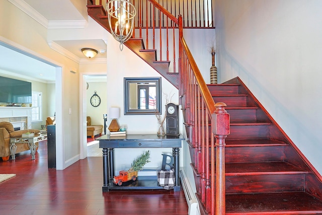 staircase with a fireplace, hardwood / wood-style floors, a baseboard heating unit, and ornamental molding