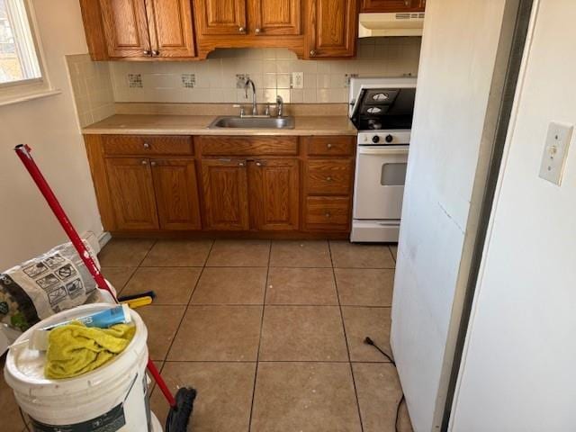 kitchen with light tile patterned floors, tasteful backsplash, white gas range, and sink