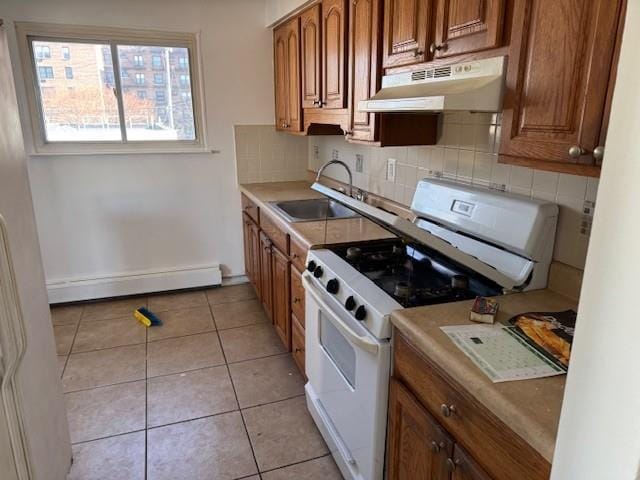 kitchen featuring tasteful backsplash, baseboard heating, white range with gas cooktop, sink, and light tile patterned floors