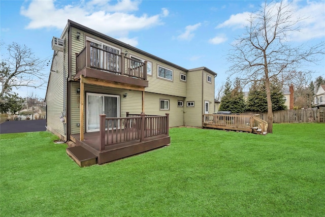 back of property with a yard, a balcony, and a wooden deck