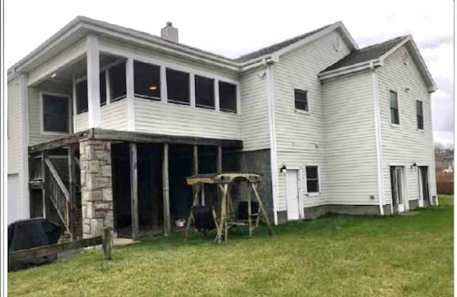 back of house featuring a lawn and a sunroom