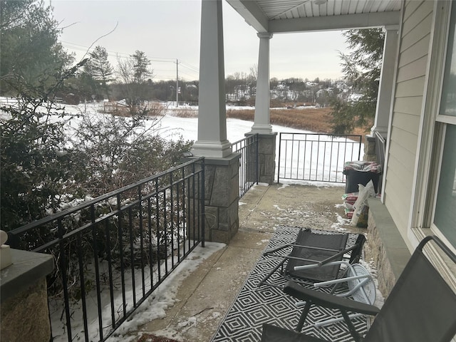 snow covered back of property featuring covered porch