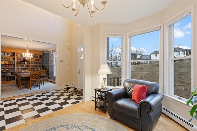 sitting room with a notable chandelier, a baseboard heating unit, light wood-style floors, a baseboard radiator, and baseboards