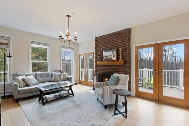 living area featuring light wood-style floors, french doors, baseboard heating, and a fireplace