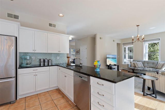 kitchen featuring tasteful backsplash, visible vents, appliances with stainless steel finishes, a peninsula, and a sink