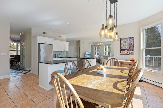 dining space featuring light tile patterned floors, a notable chandelier, visible vents, and a baseboard radiator