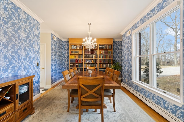 dining room featuring wallpapered walls, crown molding, and a baseboard heating unit