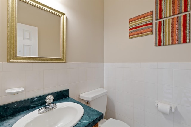 bathroom featuring vanity, tile walls, and toilet