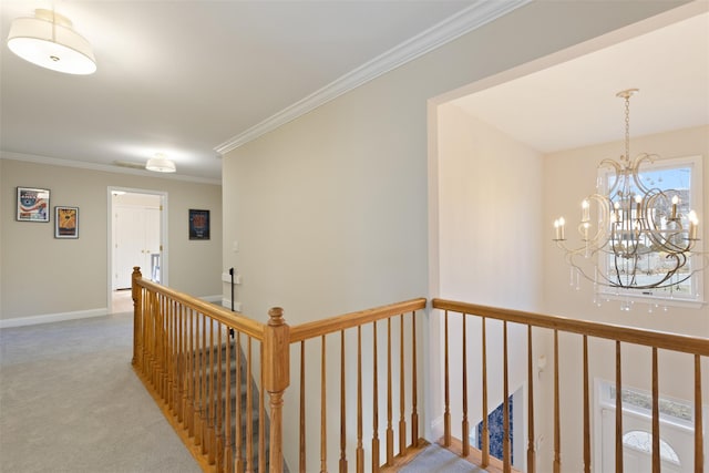 corridor featuring baseboards, carpet floors, ornamental molding, an upstairs landing, and a chandelier