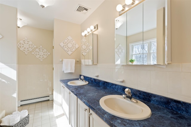 full bath featuring baseboard heating, tile walls, visible vents, and a sink