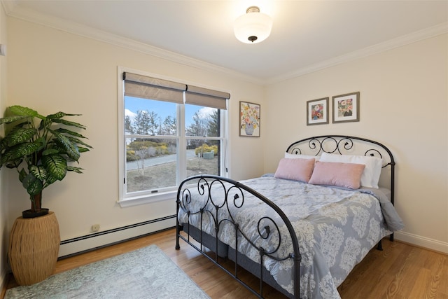 bedroom with baseboards, baseboard heating, wood finished floors, and crown molding