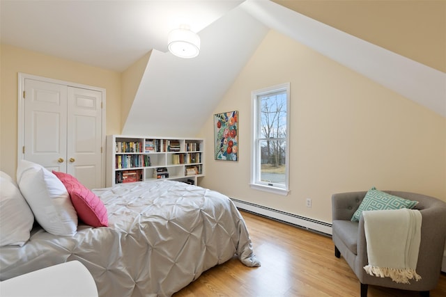 bedroom featuring lofted ceiling, wood finished floors, a closet, and baseboard heating