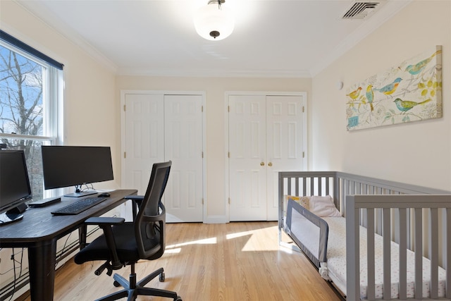 bedroom featuring visible vents, multiple closets, light wood-style flooring, and crown molding