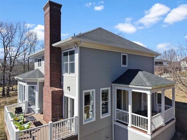 rear view of property featuring roof with shingles and a chimney