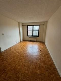 unfurnished room with dark parquet floors and a textured ceiling