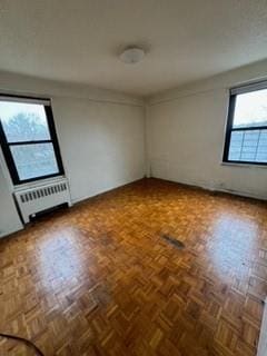 empty room featuring parquet floors and radiator