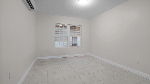 unfurnished room featuring an AC wall unit