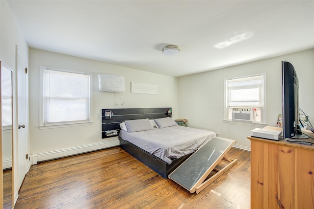 bedroom with cooling unit, dark hardwood / wood-style floors, and a baseboard heating unit