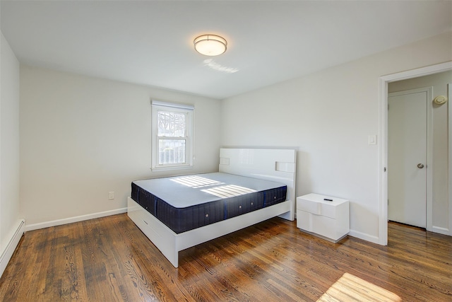 bedroom featuring a baseboard heating unit and dark hardwood / wood-style flooring