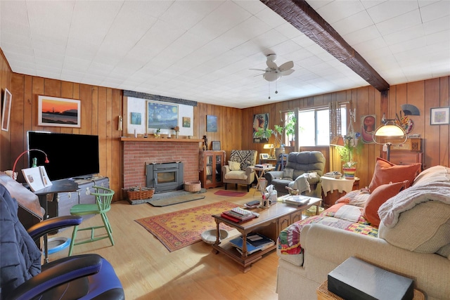 living room featuring light wood-type flooring, ceiling fan, beam ceiling, and wooden walls