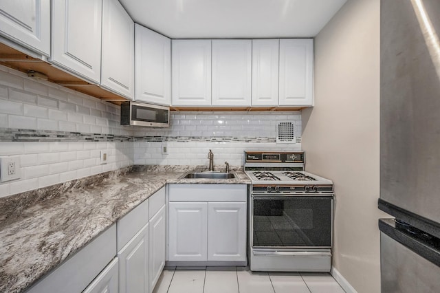 kitchen with white cabinetry, light tile patterned floors, sink, and gas range gas stove