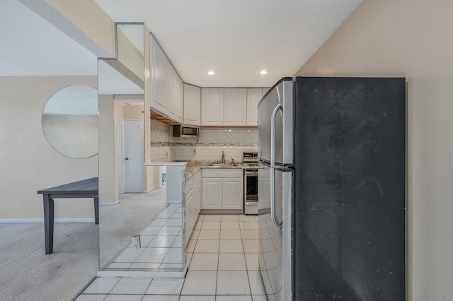 kitchen featuring light tile patterned flooring, sink, tasteful backsplash, stainless steel fridge, and white cabinets