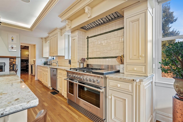 kitchen with light stone countertops, stainless steel appliances, a healthy amount of sunlight, tasteful backsplash, and cream cabinets