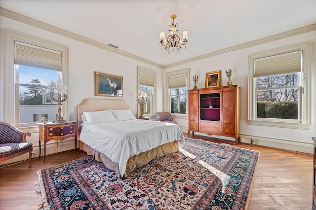 bedroom featuring multiple windows, light hardwood / wood-style flooring, crown molding, and a chandelier