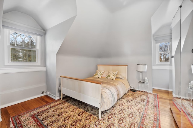 bedroom with lofted ceiling, light wood-type flooring, and multiple windows