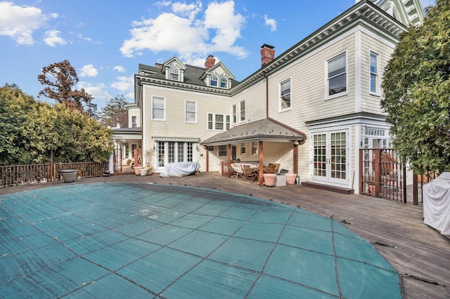 rear view of property with a pool side deck and french doors