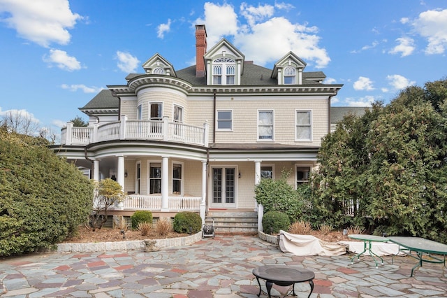 rear view of house with a patio area, a balcony, and covered porch