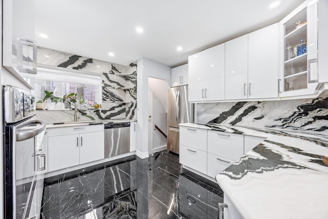 kitchen featuring white cabinets, stainless steel appliances, tasteful backsplash, and light stone countertops