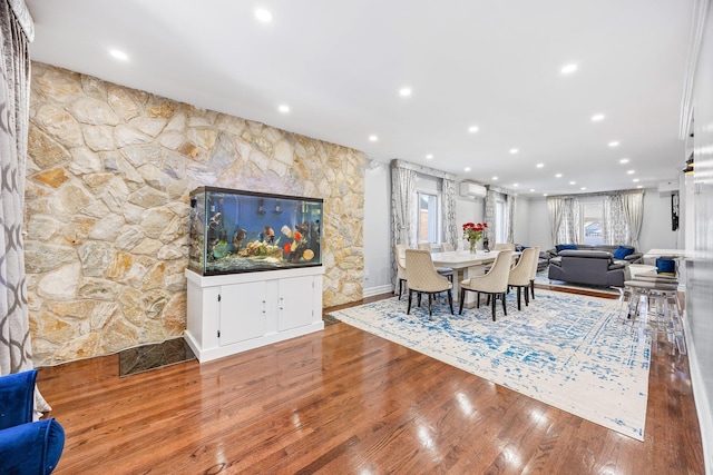 dining area featuring a wall unit AC and wood-type flooring