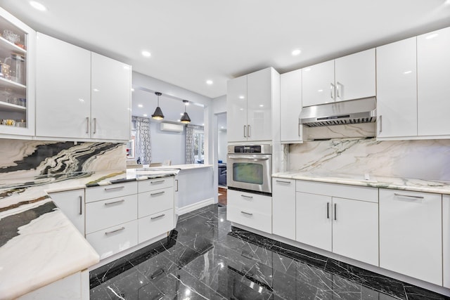 kitchen featuring pendant lighting, stainless steel oven, white cabinetry, and tasteful backsplash