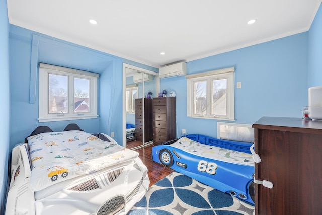 bedroom featuring hardwood / wood-style flooring, a wall unit AC, a closet, and ornamental molding