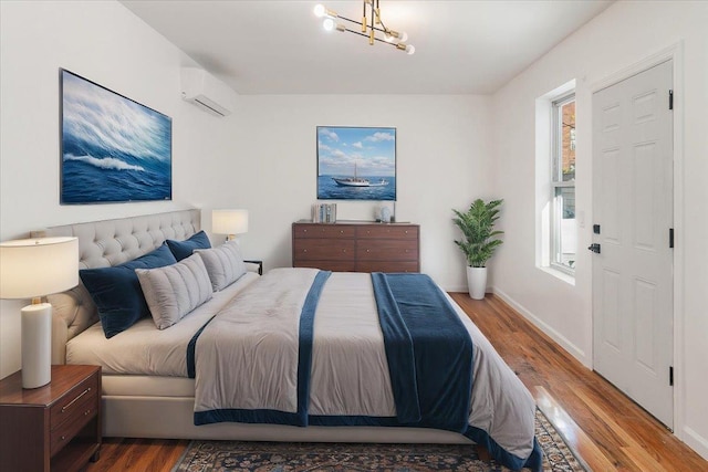 bedroom featuring a chandelier, wood-type flooring, and a wall mounted AC