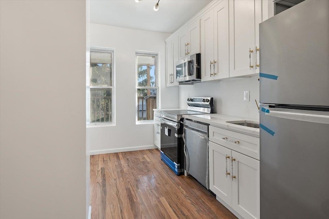 kitchen with white cabinets, appliances with stainless steel finishes, and dark hardwood / wood-style flooring