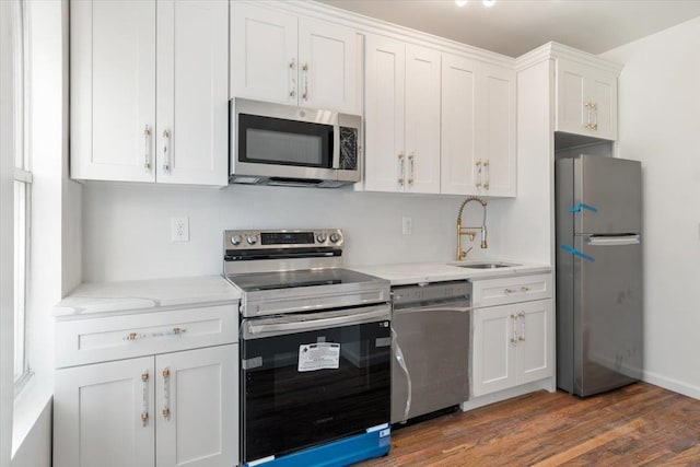 kitchen featuring light stone countertops, appliances with stainless steel finishes, dark hardwood / wood-style flooring, sink, and white cabinets