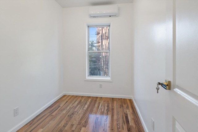 empty room with an AC wall unit and dark hardwood / wood-style flooring