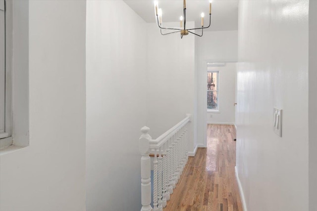 hall with a notable chandelier and hardwood / wood-style flooring