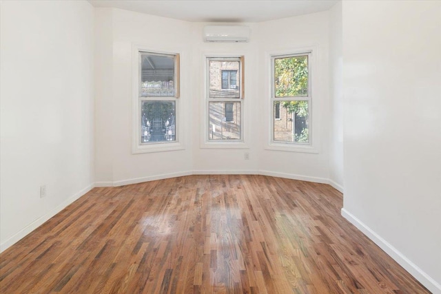 unfurnished room with wood-type flooring and a wall unit AC