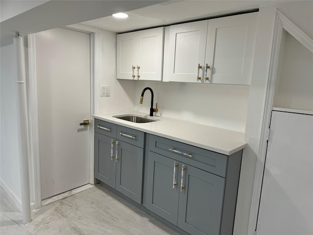 kitchen featuring white cabinets, gray cabinetry, and sink