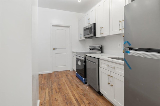 kitchen featuring light hardwood / wood-style floors, light stone counters, white cabinetry, and stainless steel appliances