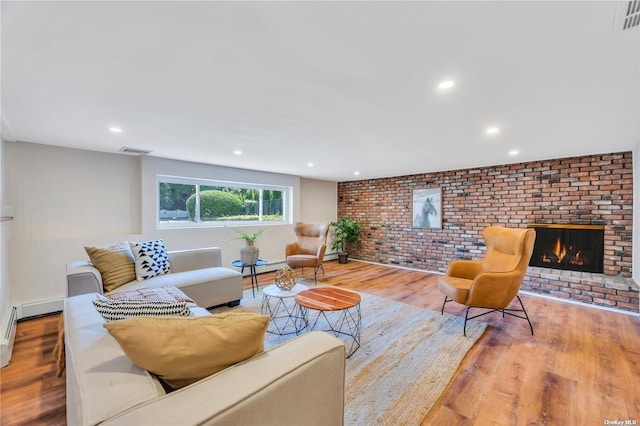 living room featuring light hardwood / wood-style flooring, a brick fireplace, and brick wall