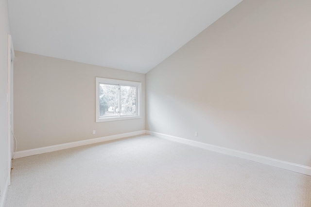 spare room featuring light carpet and vaulted ceiling