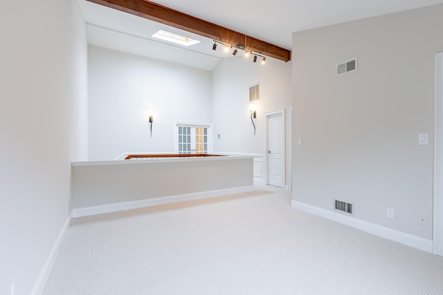 empty room featuring light carpet, beamed ceiling, track lighting, and high vaulted ceiling