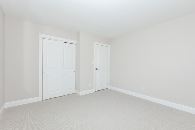 unfurnished bedroom featuring a closet and light colored carpet