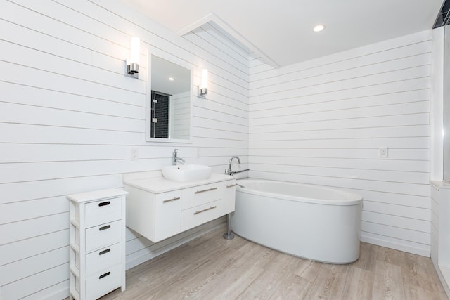 bathroom featuring a washtub, hardwood / wood-style floors, vanity, and wooden walls